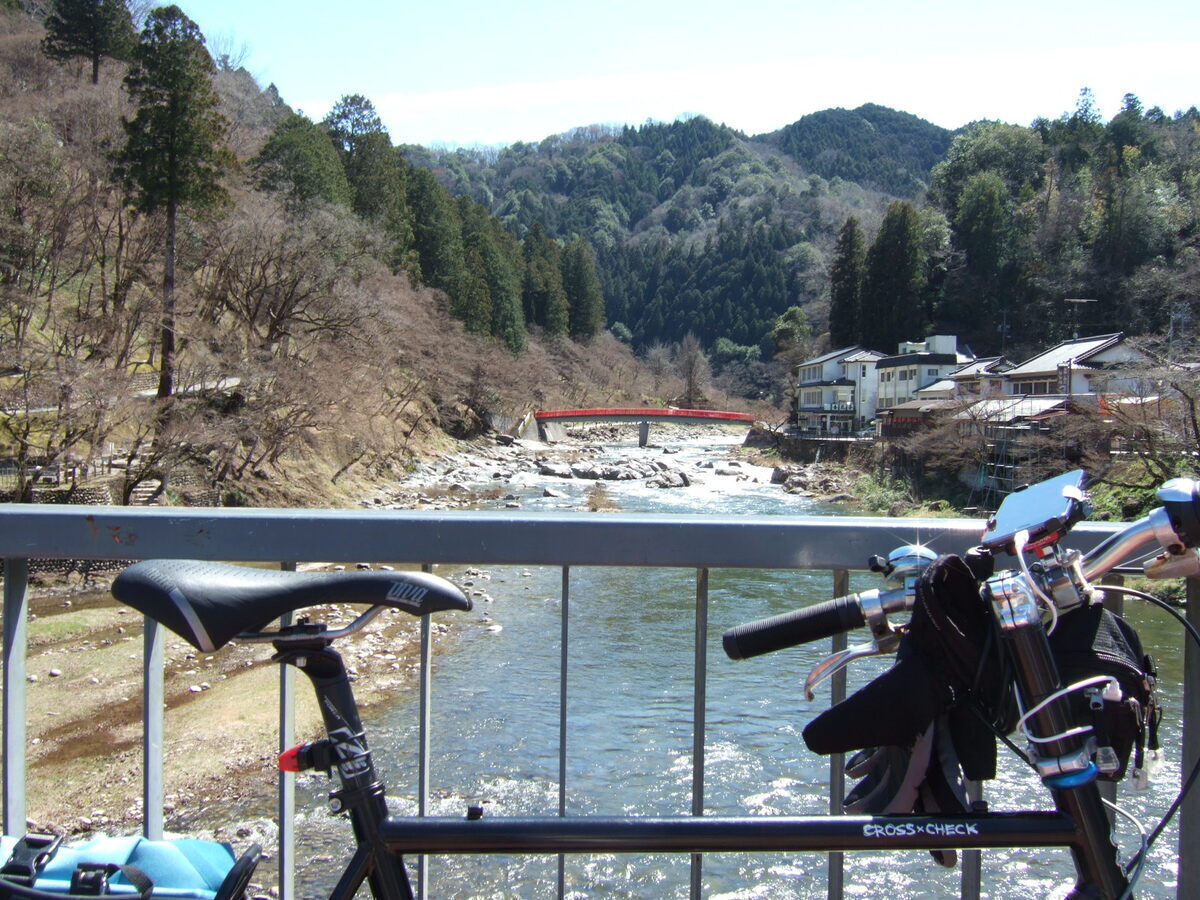 A view down a mountain stream. A bridge, probably an elevated pipeline crossing the stream, is in the distance.