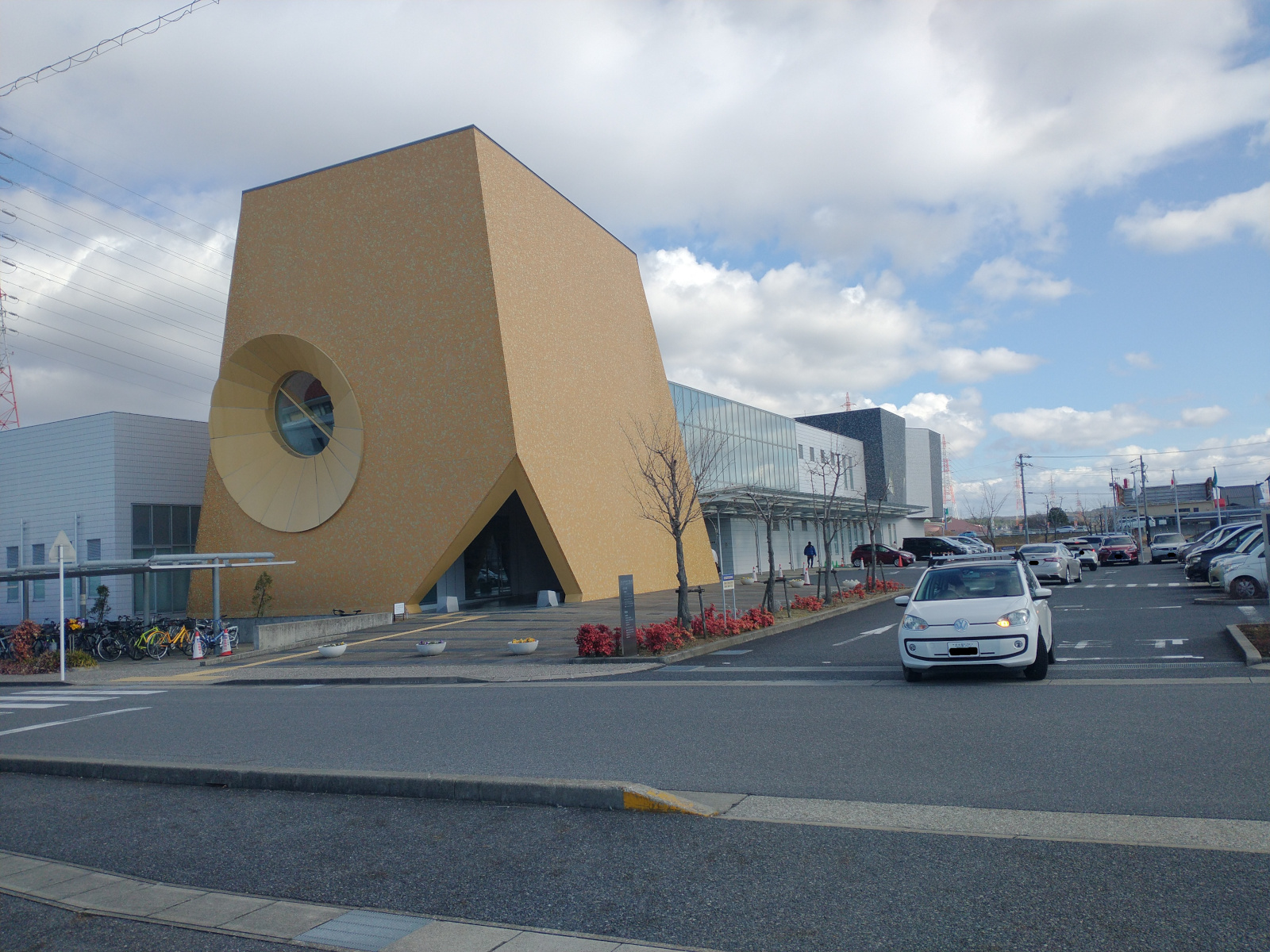 A two-story concrete building, with a four-story tiled box set over its corner for decorative effect, with a window in the side facing the street resembling a funnel or conical cut-out