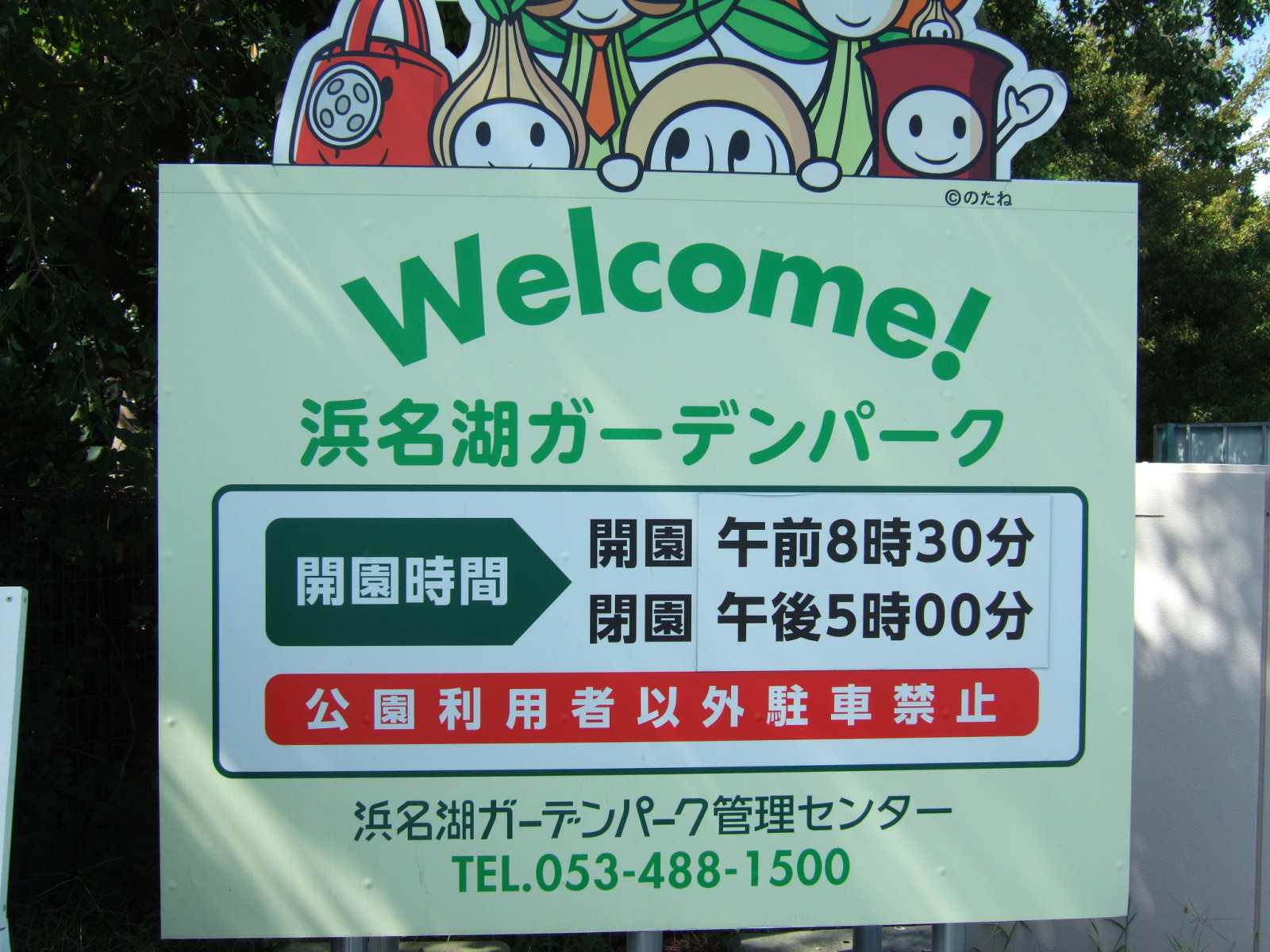 The sign at the gate of Hamamatsu Garden Park, reading:\n"Welcome! 浜名湖カーデンパーク"\nand stating the opening hours of the parks to be 8:30am to 5:00pm, and giving the phone number of the administrative office.