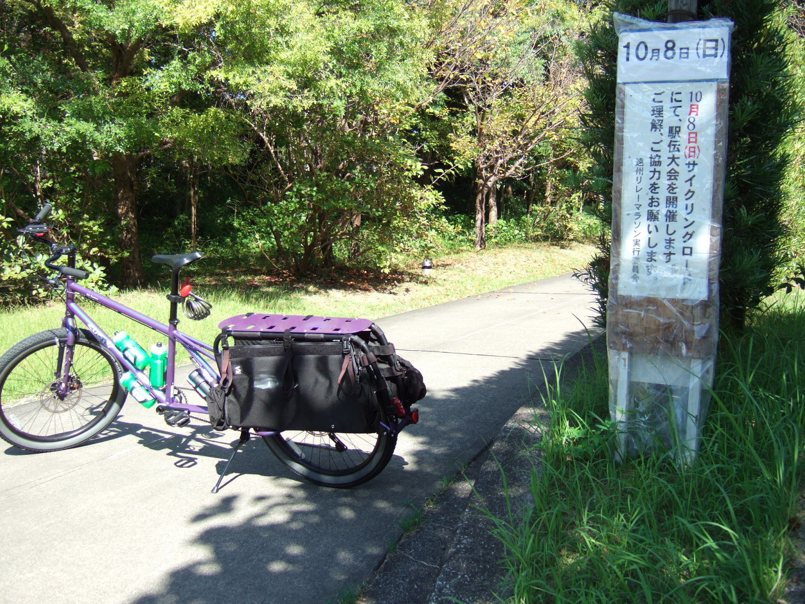 A cargo bike parked next to a sign reading (in translation):\n\nOctober 8th (Sunday)\nAn eki-den event will be held on the Cycling Course on Oct. 8. We ask your understanding and cooperation.\n—Enshu Relay Marathon Executive Committee