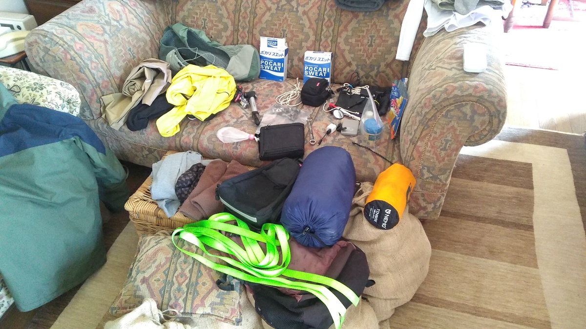 A collection of travel gear for a bicycle trip laid out on a couch.