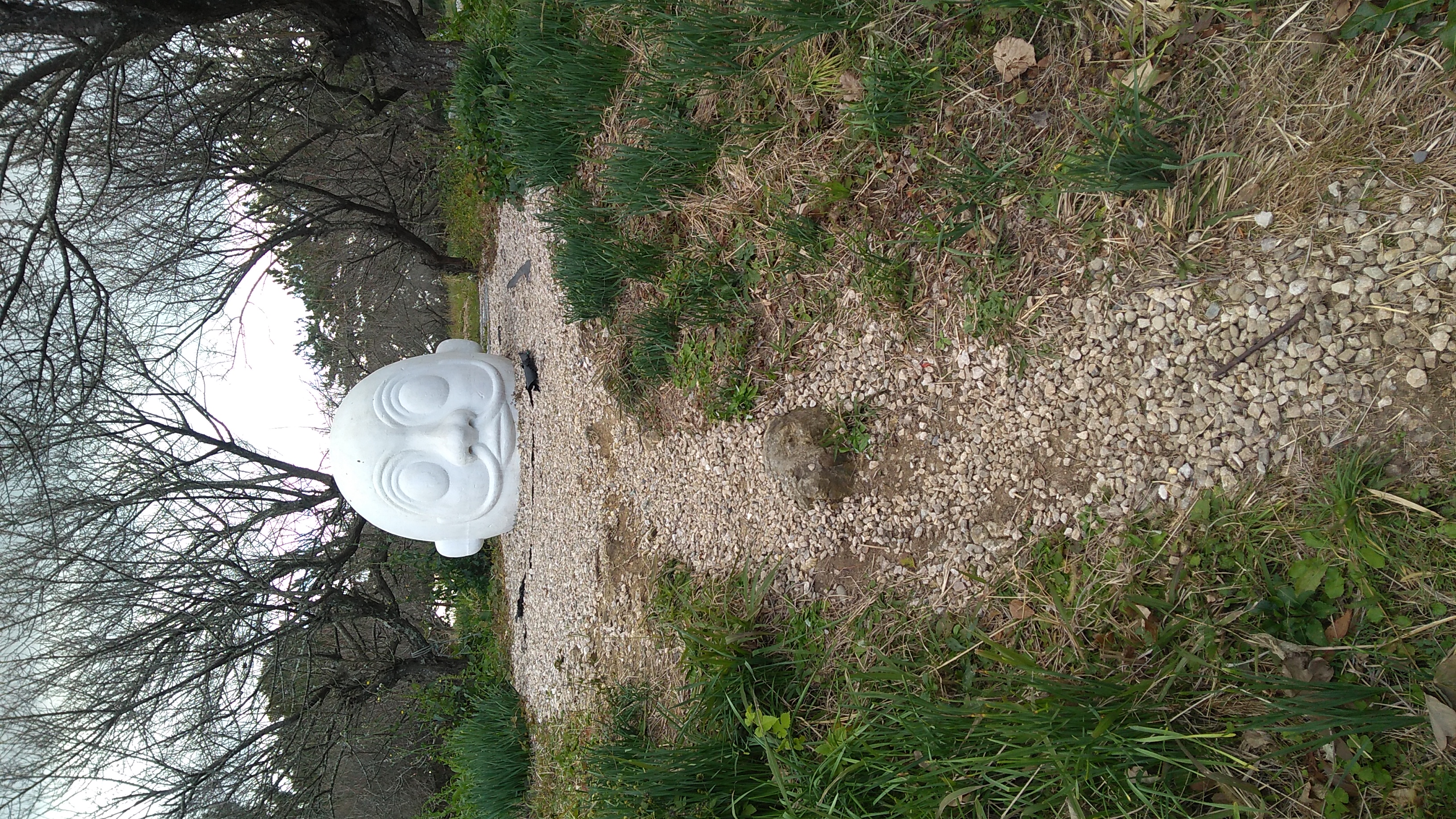 A cast ceramic sculpture of a large white sylized head.