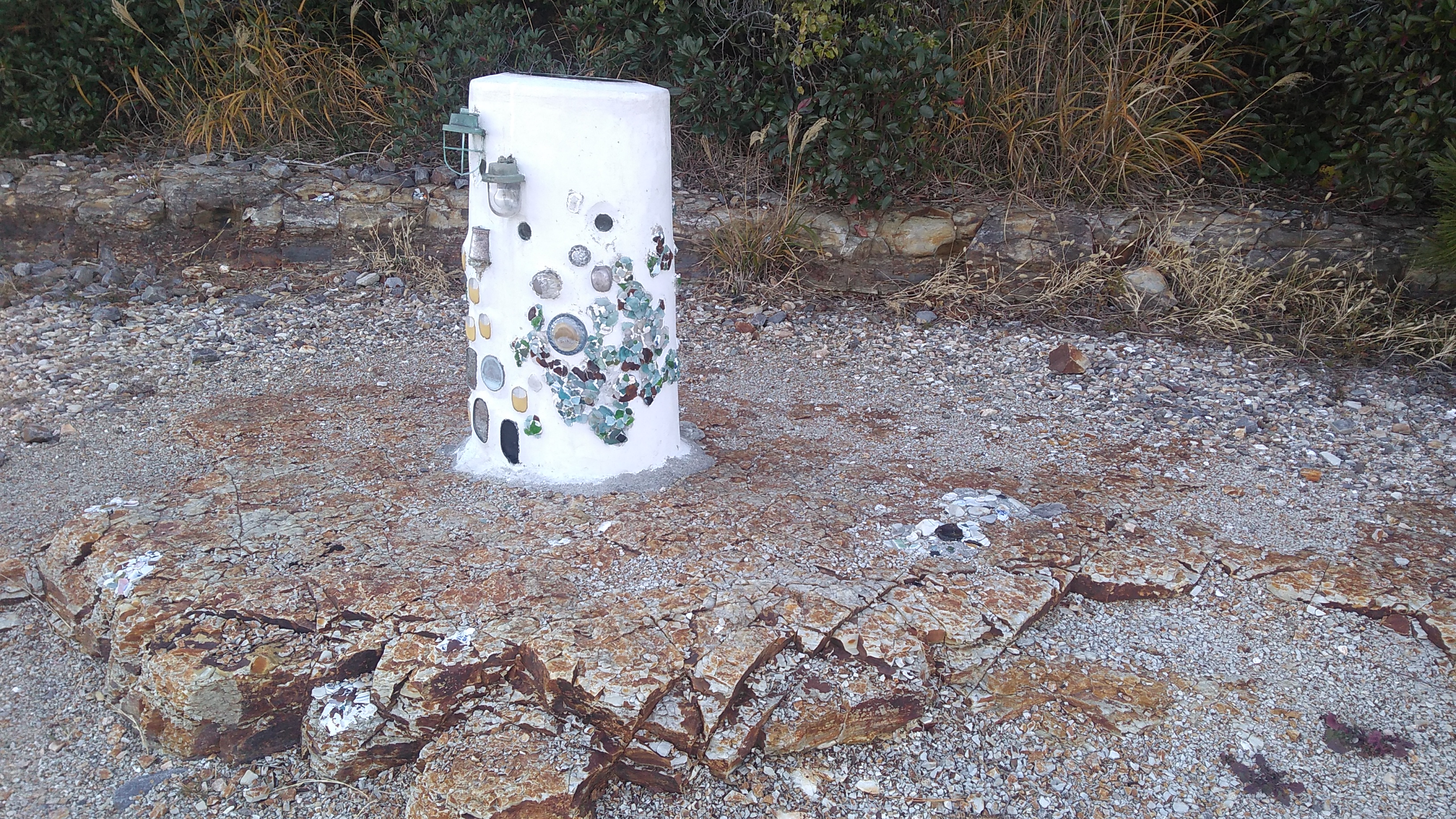 A white ceramic pillar adorned with ships’ lanterns and other bits and pieces.