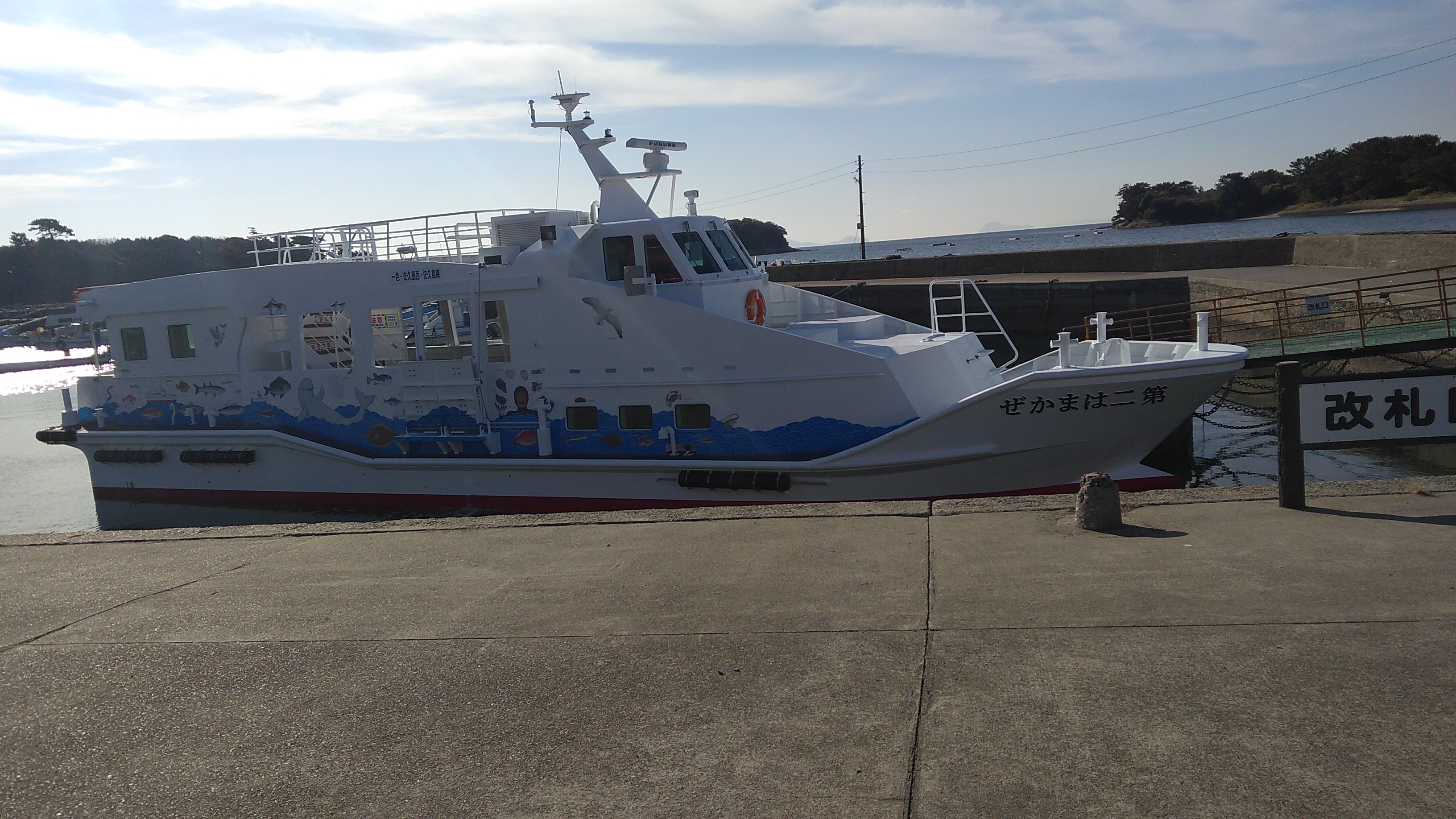 A small modern ferry in white and blue livery docked at a concrete pier.