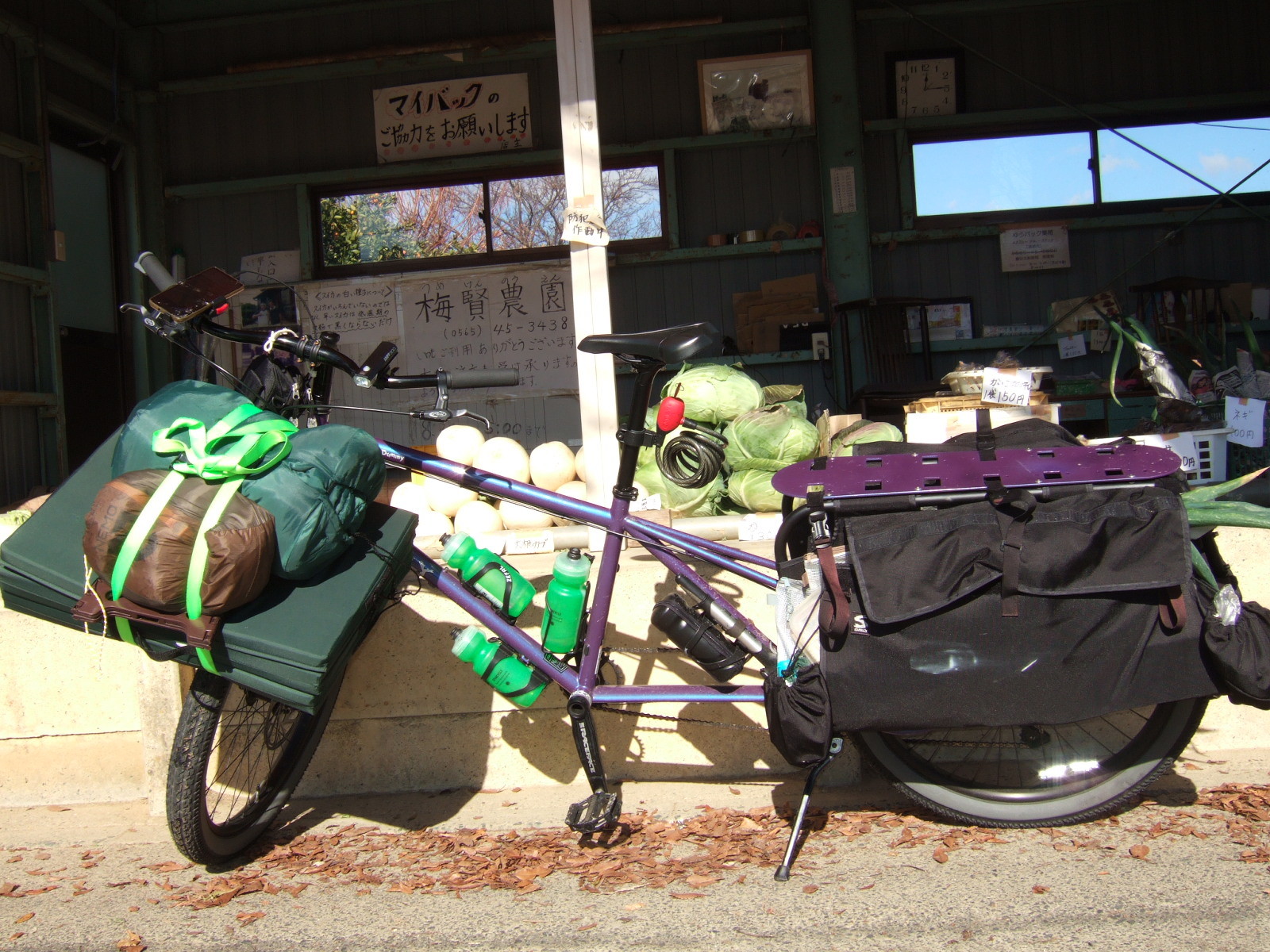 A closer view of the cargo bike parked in front of a vegetable stand.