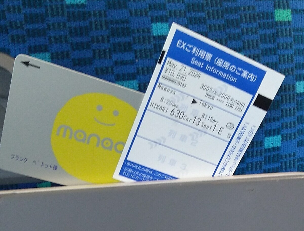 A Shinkansen ticket wedged into a fitting on the back of the seat in front. The ticket shows a date of March 21, 2024, for Nagoya to Tokyo on Hikari 630, in Carriage 13, Seat 1-E.